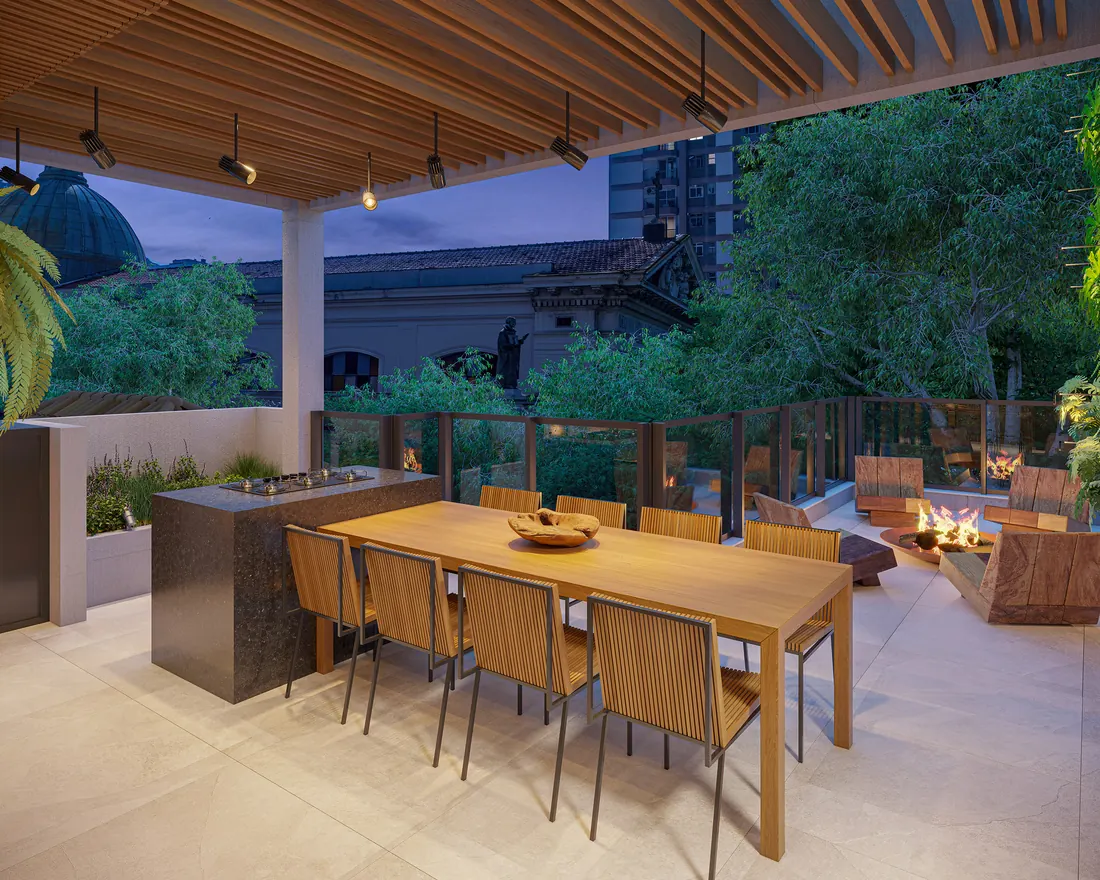 Terraço gourmet do Casa Mariana Loft Residencial com mesa sob pergolado de madeira e lounge
